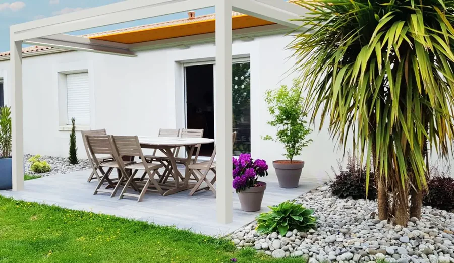 Pergola blanche à store enroulable avec toile jaune au-dessus d'une table de jardin