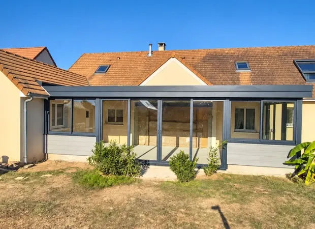 Extension à toit plat près du Mans : façade vitrée et menuiseries gris foncé
